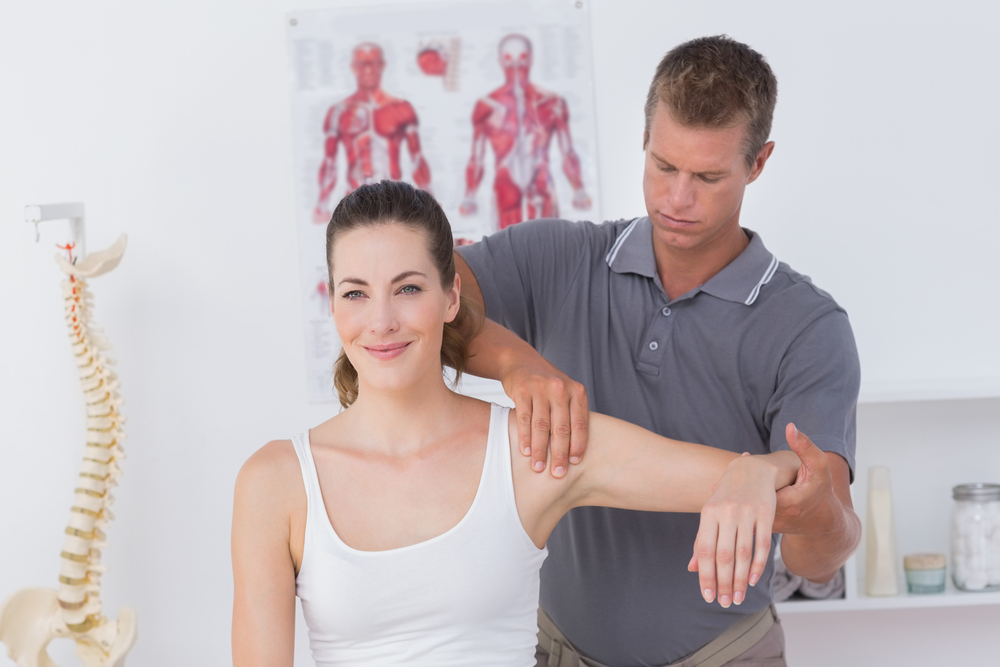 Doctor stretching a young woman arm in medical office